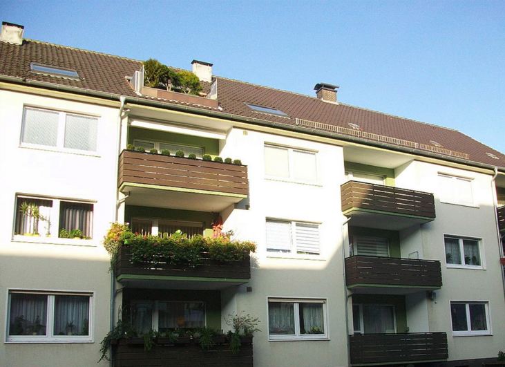 Weißes Mehrfamilienhaus mit dunklen Holzbalkonen